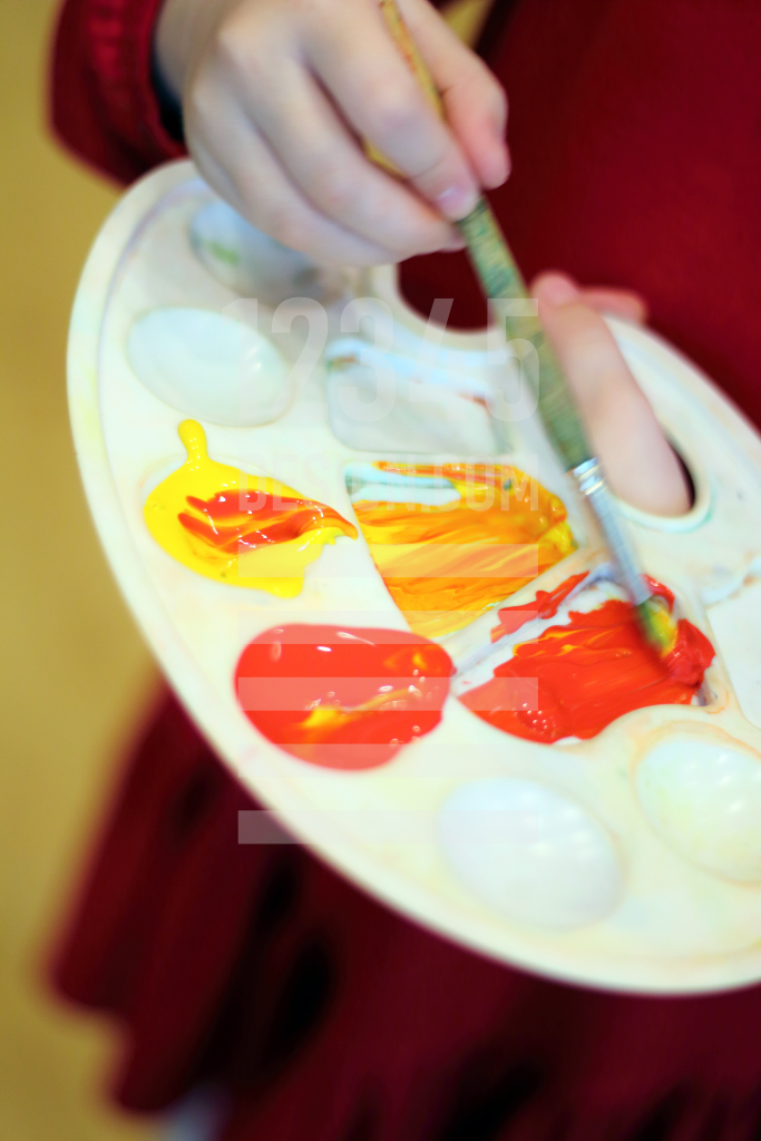 Mixing yellow and red paints on the palette